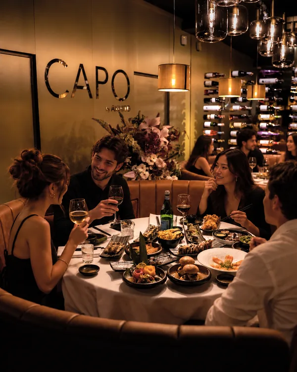 Gasten delen gerechten en wijn aan de ronde tafel bij CAPO